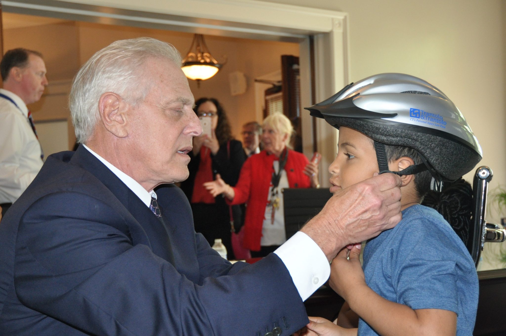 Vincent Trantolo putting a bicycle helmet on a child